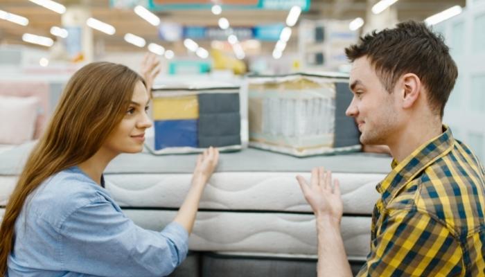 Two people comparing different mattress types