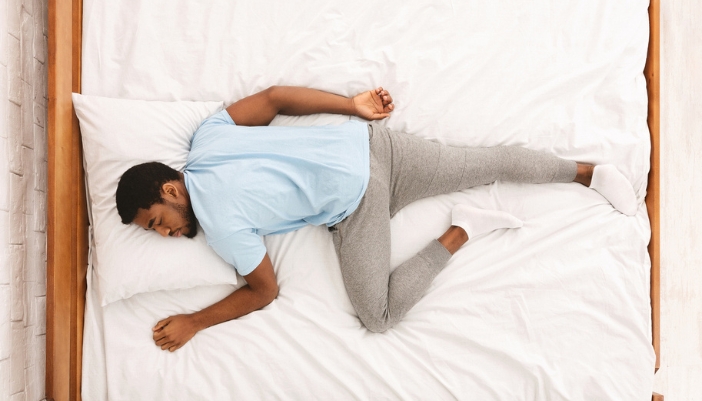 A man lays on his stomach as he sleeps.