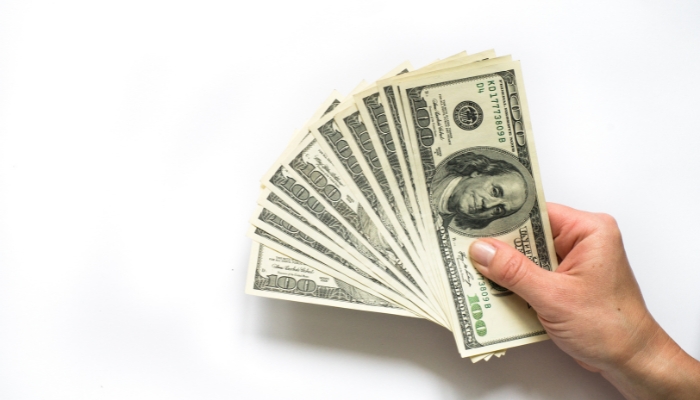 Hand holding cash in front of mattress