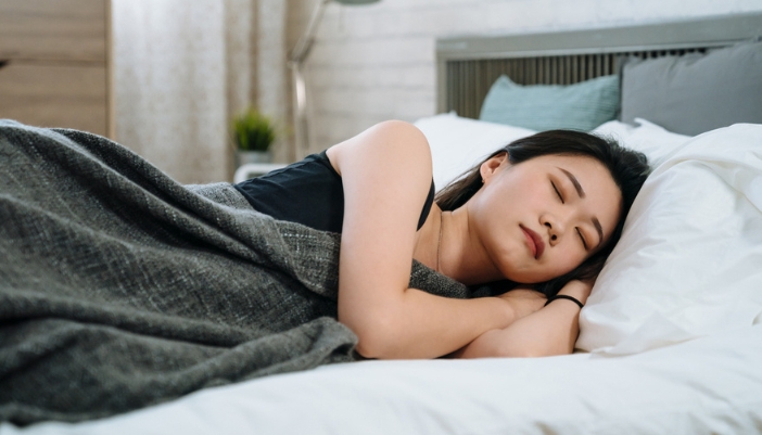 A woman sleeps soundly on her side in bed.