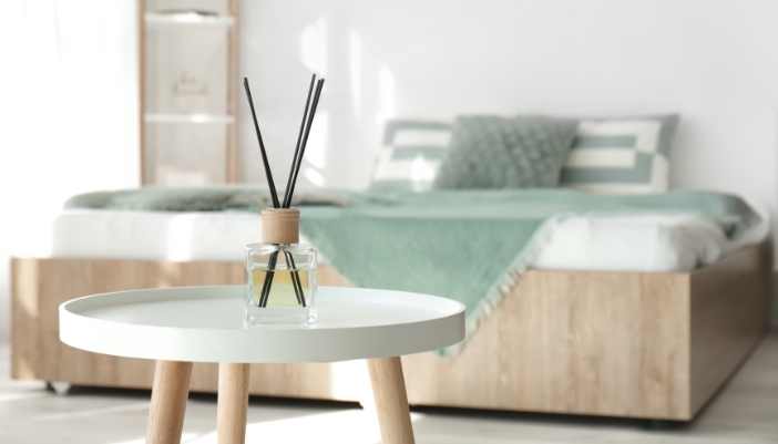 Matt_DIY-Aromatherapy-Solutions_3.jpg Closeup of a reed diffuser on a table in front of a bed
