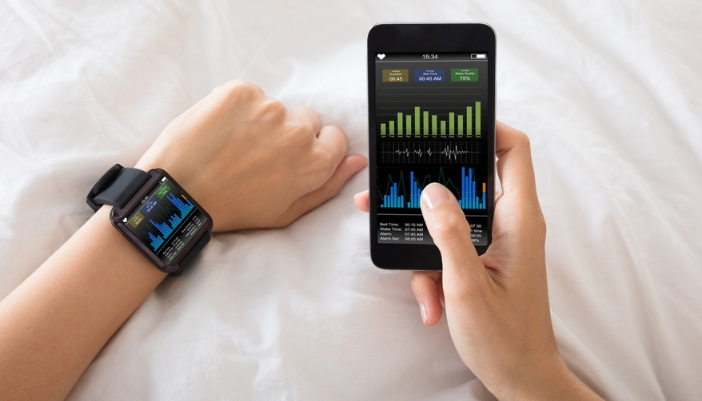 A pair of hands checks a sleep tracking app on both their smartphone and smart watch.