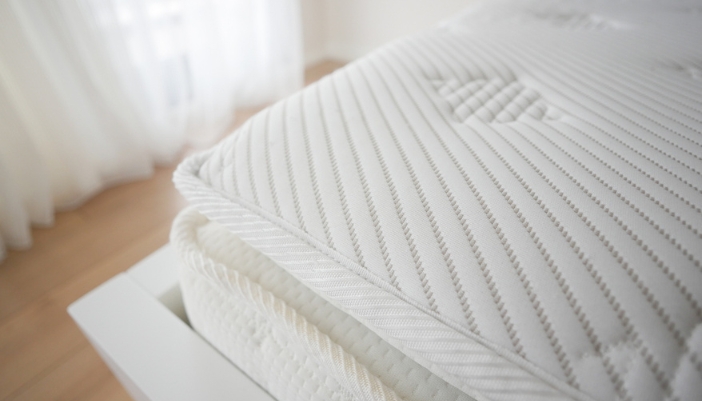 A close-up of a thick mattress protector on top of a clean mattress.