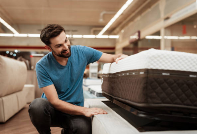 View of a man examining a mattress in a mattress store