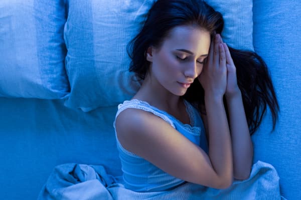Overhead view of a woman sleeping on a mattress in a blue filter