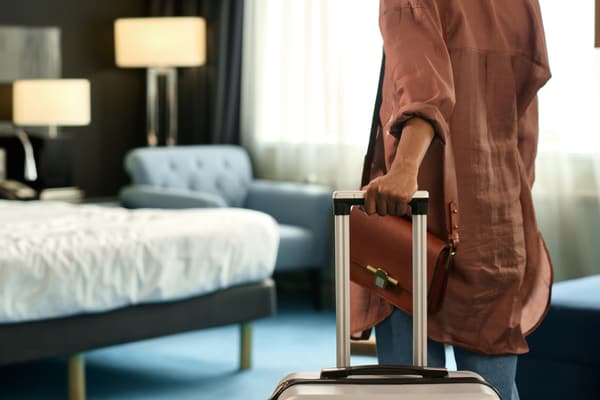 iStock Credit: mediaphotos A woman with a suitcase entering a bedroom