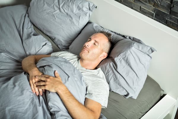 iStock Credit: LSOphoto Overhead view of man sleeping on his back in a bed