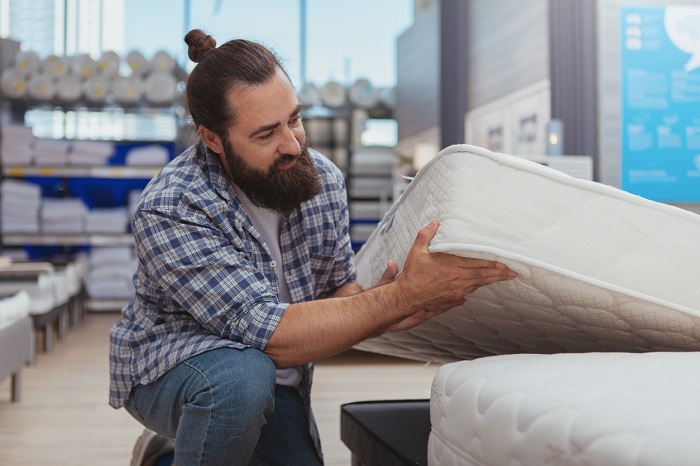 Man testing innerspring mattress in mattress 