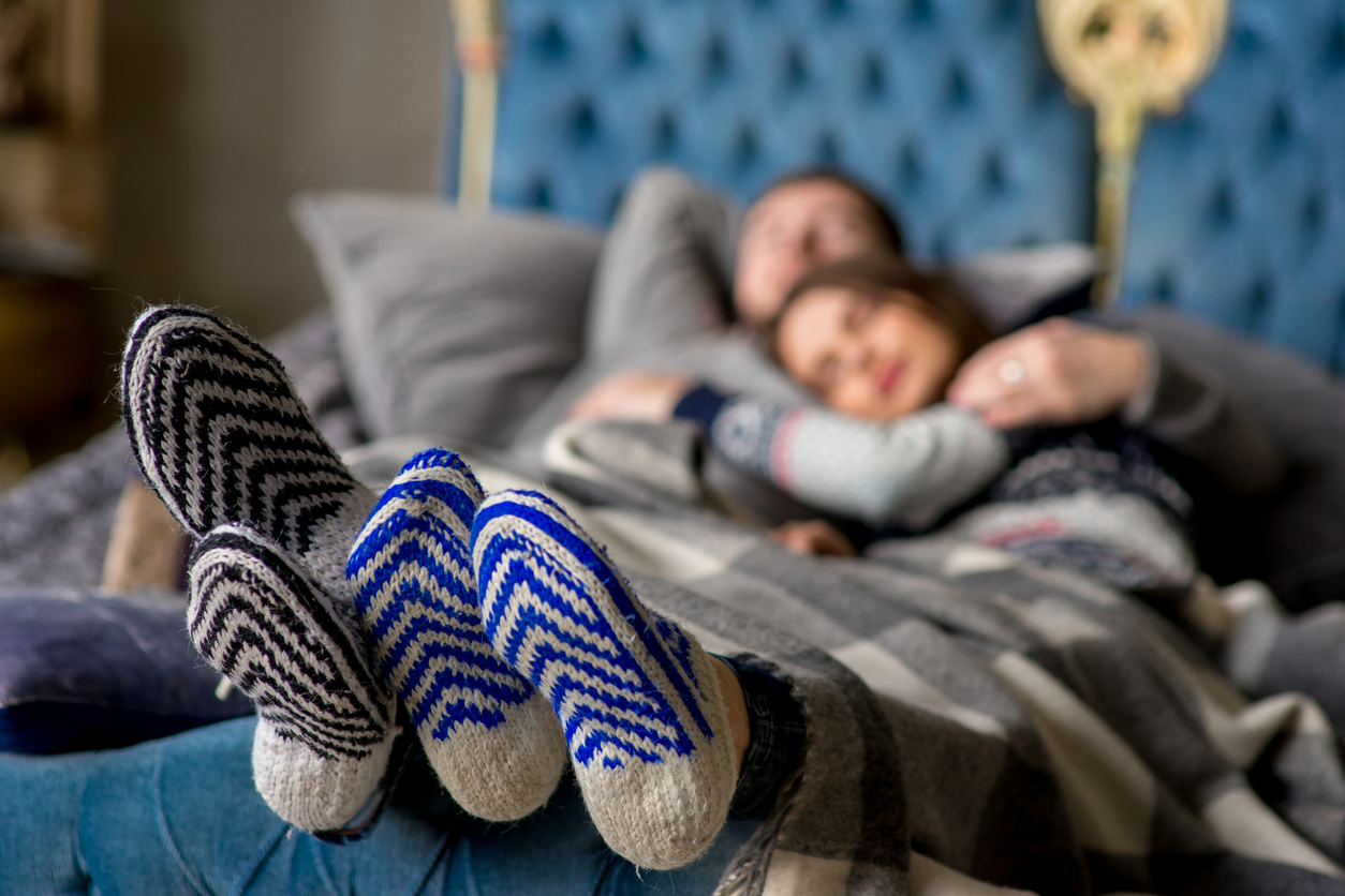 couple snuggles in bed with fuzzy socks on