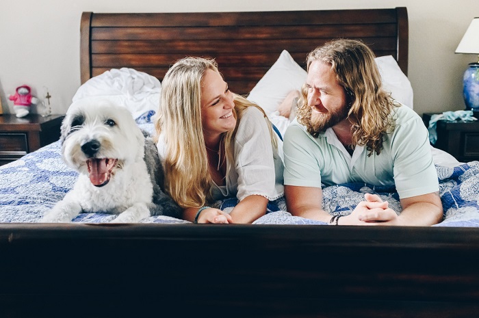 Lisa5201 Couple lying in bed at home in their bedroom happy and smiling with their dog.