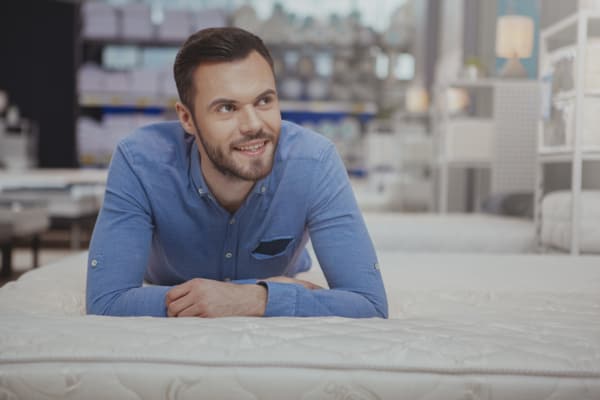 iStock Credit: Oleksandra Polushchuk A man smiling on a mattress