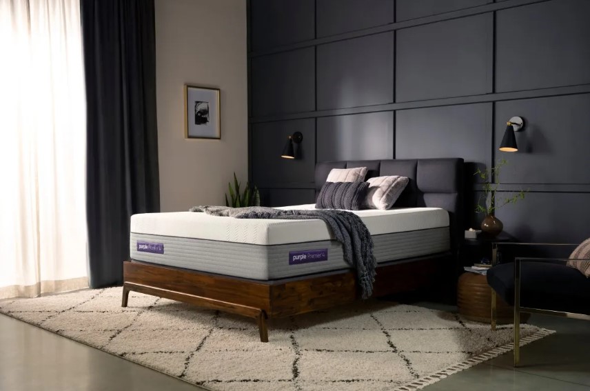 Purple mattress on a wood and upholstered bed frame in a bedroom