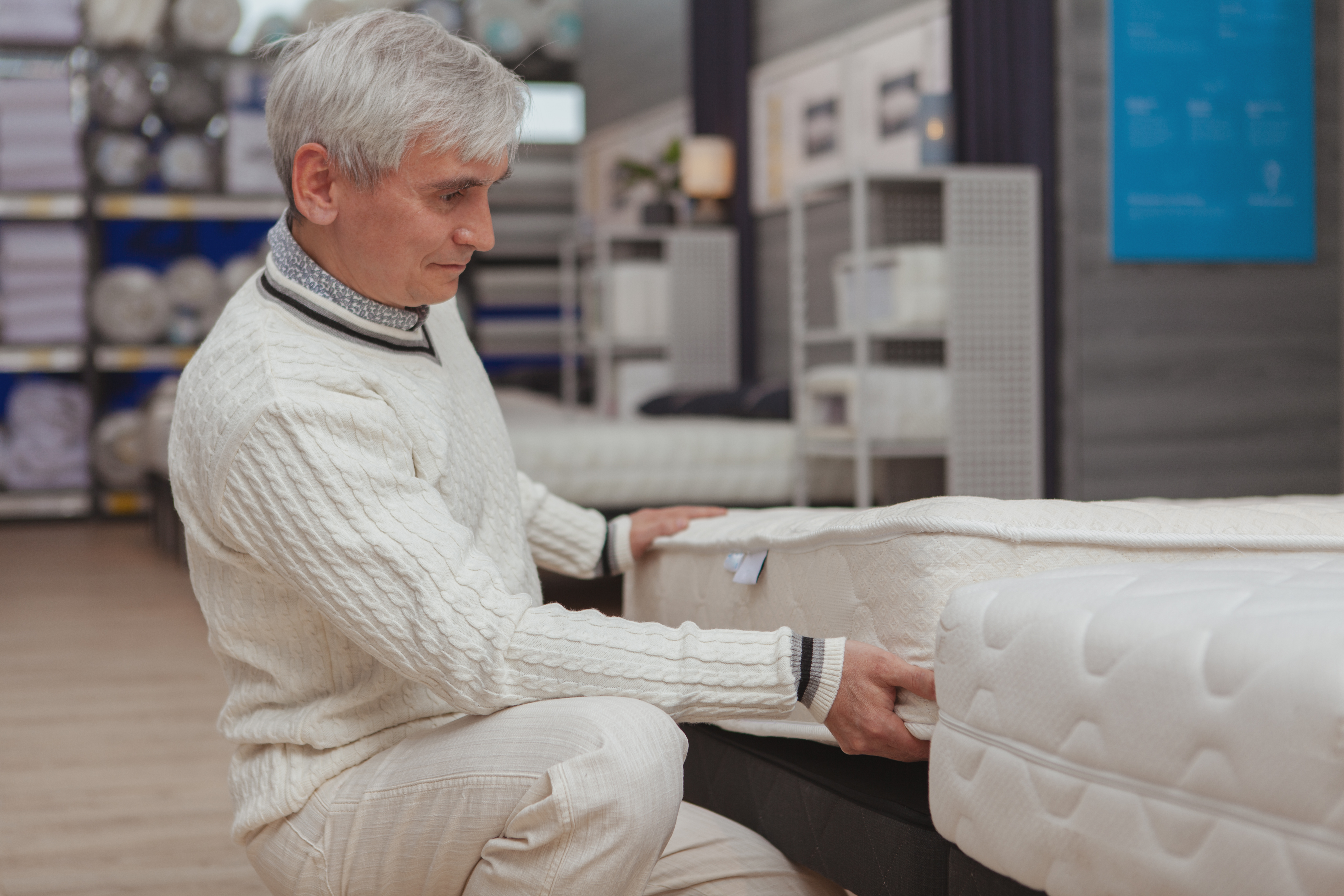 An elderly man shopping for a mattress 