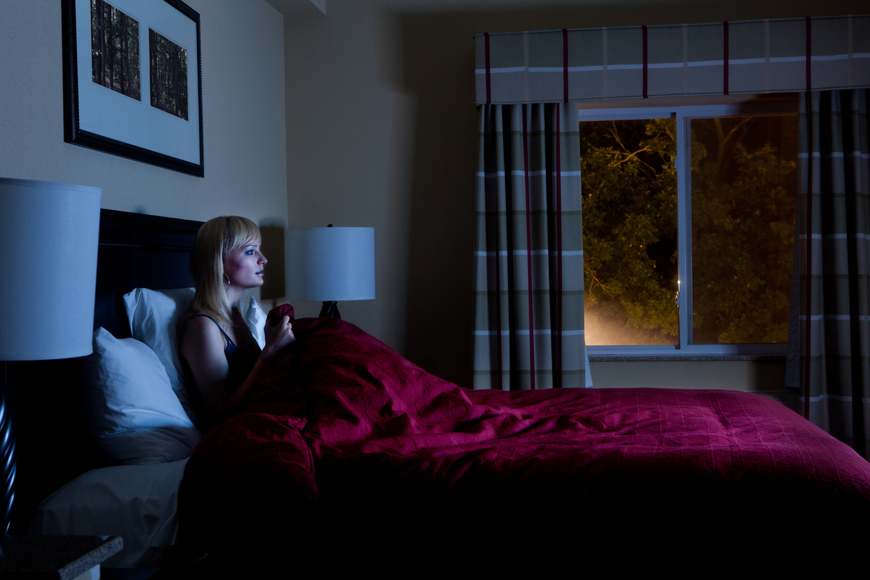 iStock Credit: DrGrounds Woman watches TV in bed and is illuminated by screen light