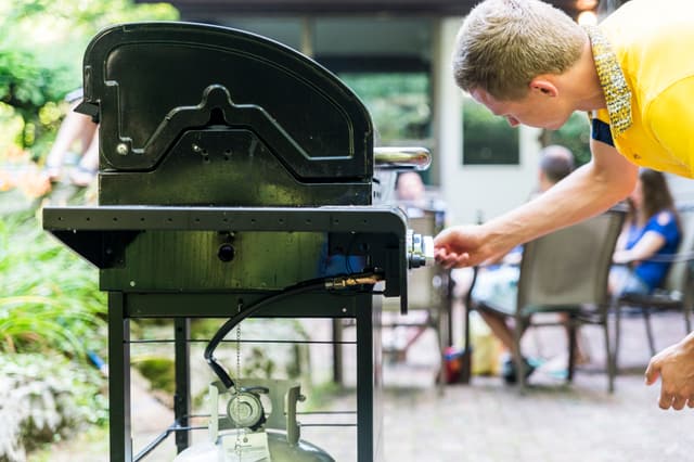 Credit: iStock Side view of a man igniting his gas grill