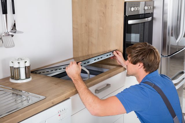Front view of a handyman installing a flat-top cooktop in a kitchen