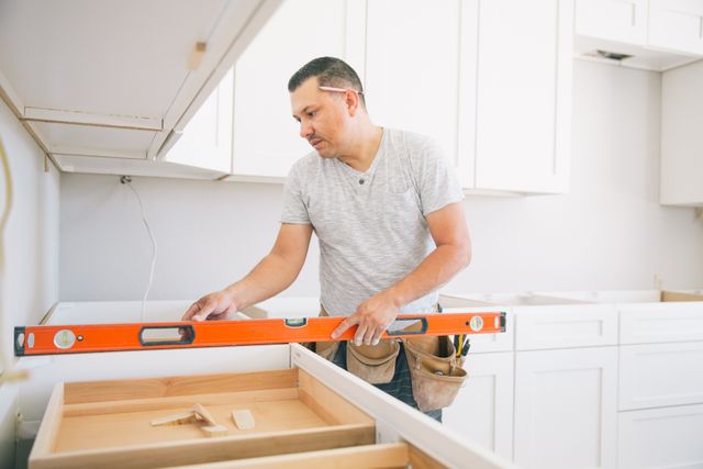 Front view of a man measuring the counter for a slide in range installation