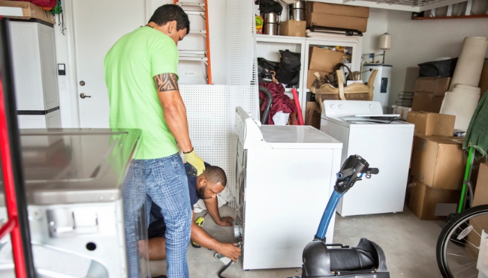 Closeup of someone fixing a dryer in a garage