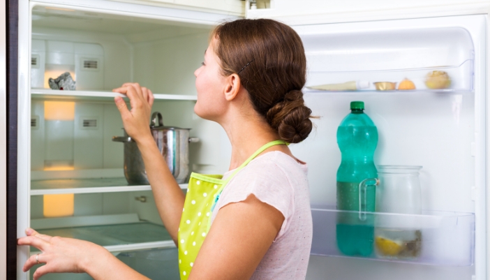 Woman checking on her fridge that isn’t cooling