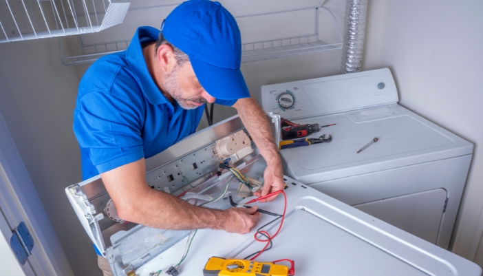 An appliance technician fixing the electric components on a washer