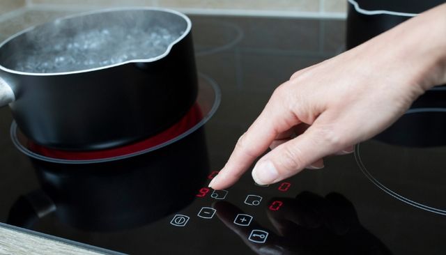 Close view of a person adjusting the controls on a glass top electric cooktop
