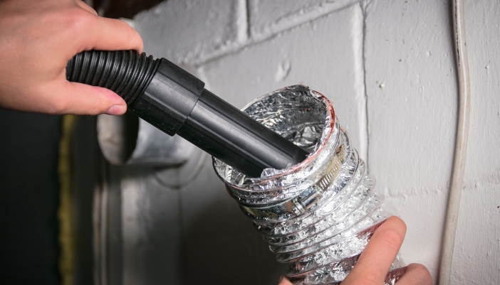 Serv_Dryer-Smells_1.jpg Closeup of someone vacuuming out the dryer vent hose