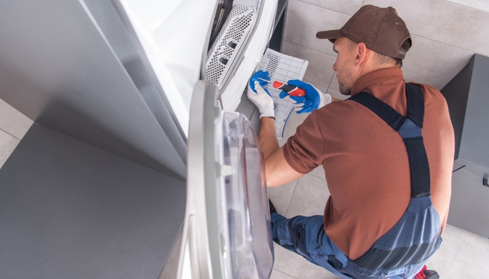 Serv_Dryer-Smells_5.jpg Closeup of service repairman fixing a dryer