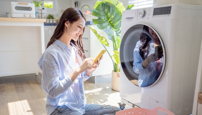 Serv_Smart-Laundry-Troubleshooting_1.jpg Happy woman who finished diagnosing the small issue on her washer
