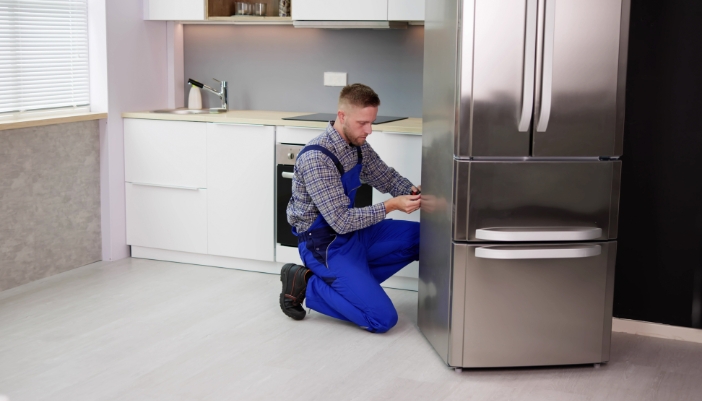 Serv_Summer-Fridge-Optimization_2.jpg Serviceman cleaning the condenser coils on the back of the fridge