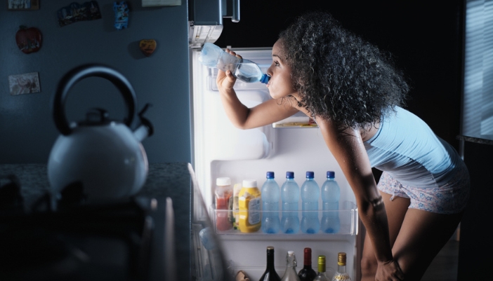 Serv_Summer-Fridge-Optimization_4.jpg Woman taking a drink from a well-organized fridge