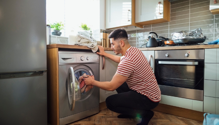 Serv_Washer-Dryer-Combo-Problems_2.jpg Man rearranging clothes to minimize vibration