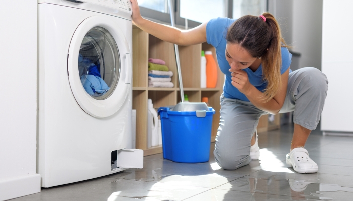 Serv_Washer-Dryer-Combo-Problems_6.jpg A woman inspecting her washer dryer combo leaking water
