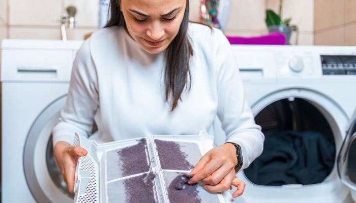 Woman cleaning lint trap from dryer