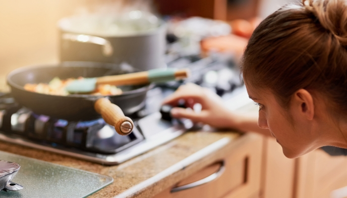 Closeup of a woman adjusting the flame on her gas burner