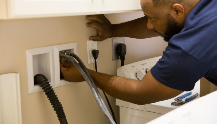 Closeup of someone connecting the washing machine hoses correctly