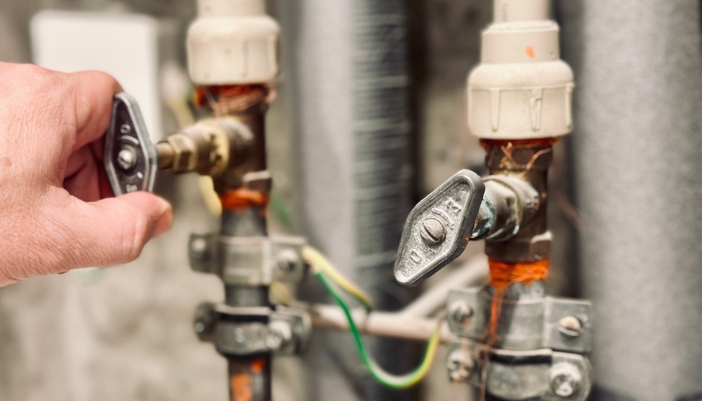 Closeup of a hand closing turning a water shutoff valve