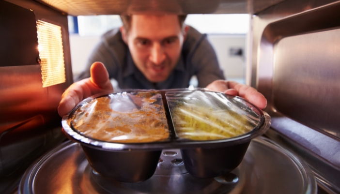 Serv_Repair-vs-Replace-Microwave_1.jpg Interior closeup of a man placing food in a microwave