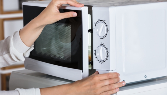 Serv_Repair-vs-Replace-Microwave_2.jpg Closeup of someone having trouble opening the microwave door