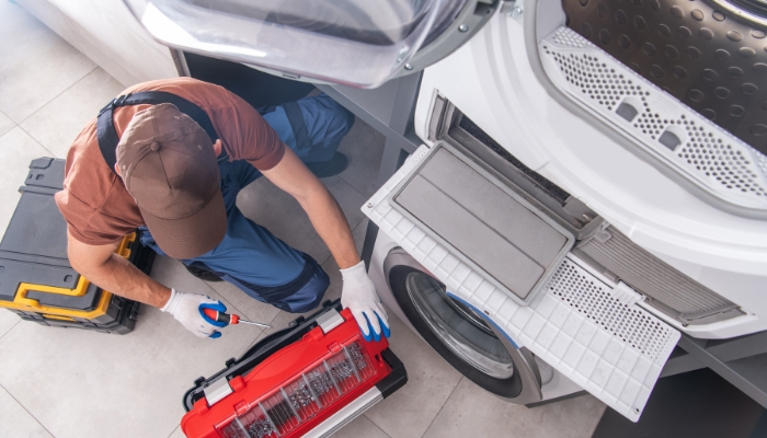 Service technician working on a stacked washer and dryer unit