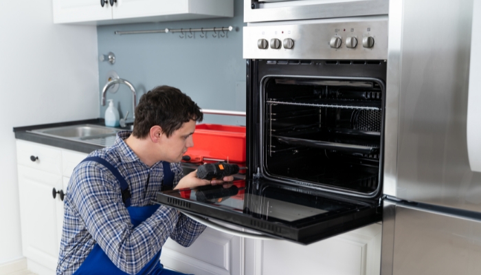 Service technician is screwing in loose parts of the oven door