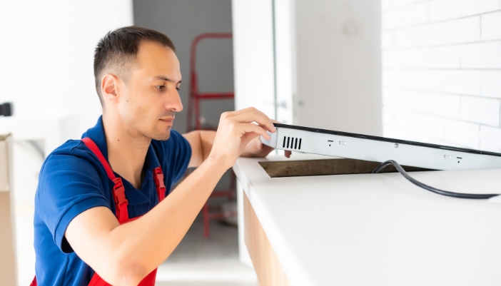 Service repair tech fixing a cooktop
