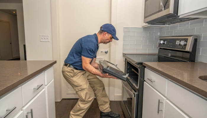 Serv_Top-Range-Issues_2.jpg Service repairman fixing the oven door on a range