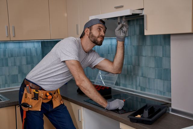 Front view of a man installing an under cabinet range hood