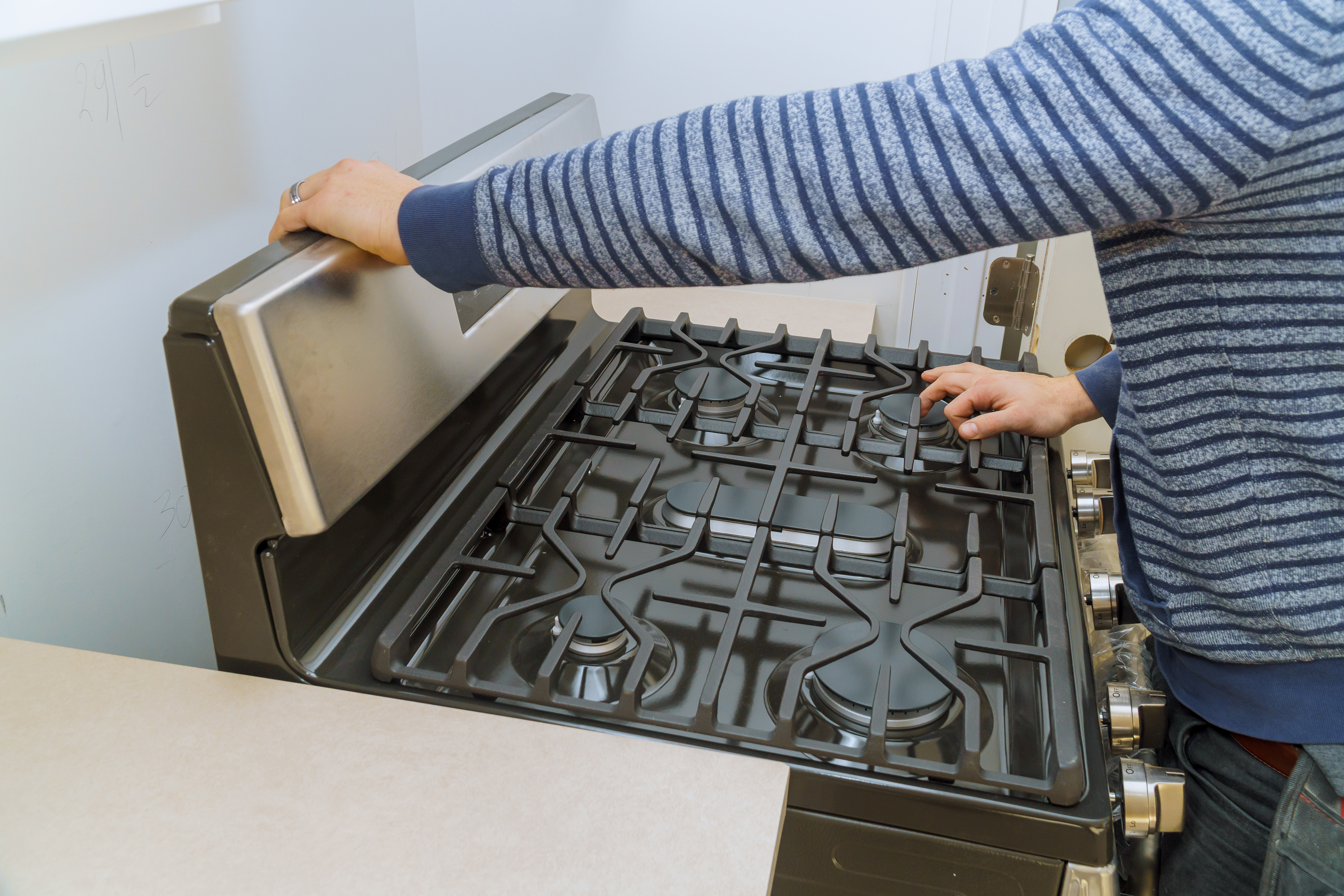 View of a man installing a gas range in a casual kitchen View of a man installing a gas range in a casual kitchen