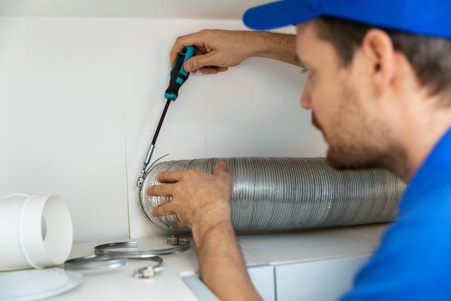 Credit: iStock Front view of a man installing the vent of a vented dryer
