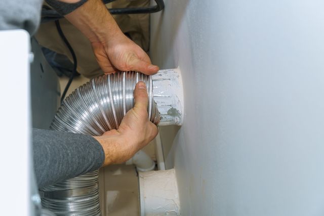 Credit: iStock Front view of a man installing a vent for a vented dryer