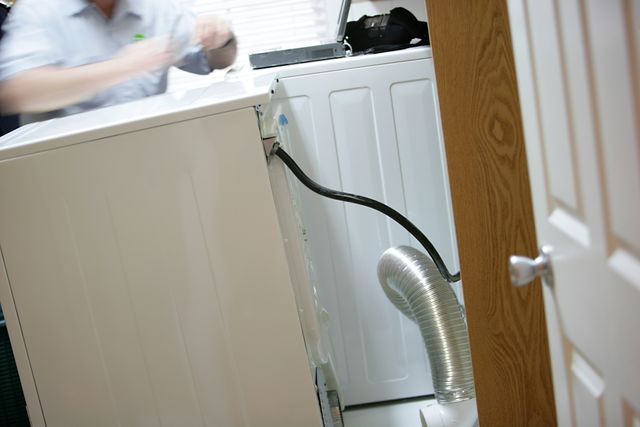 Credit: iStock Side view of a man installing a vented dryer