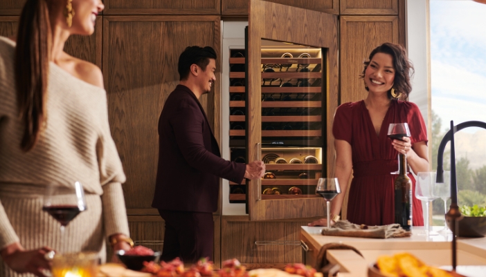 Elegantly dressed people have a dinner party at home in a modern kitchen.
