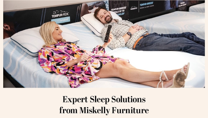 A couple lays on a bed in a showroom and tests the features.