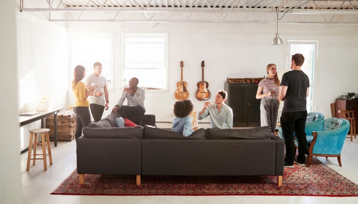 A group of friends having a party at home with a variety of furniture and drinks.